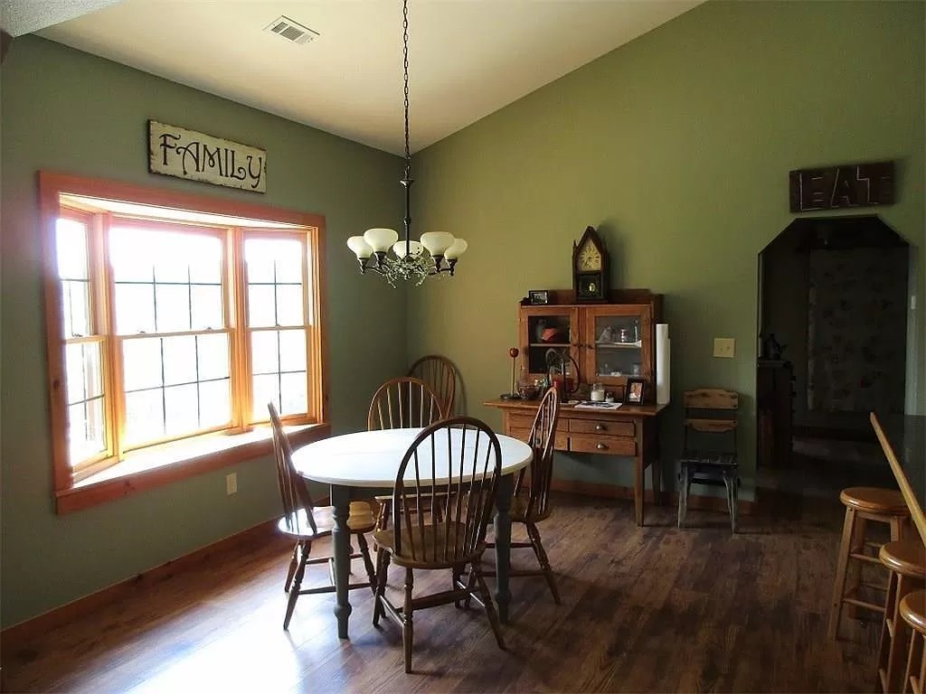 The bright dining room of the log house with a round table and wood floors
