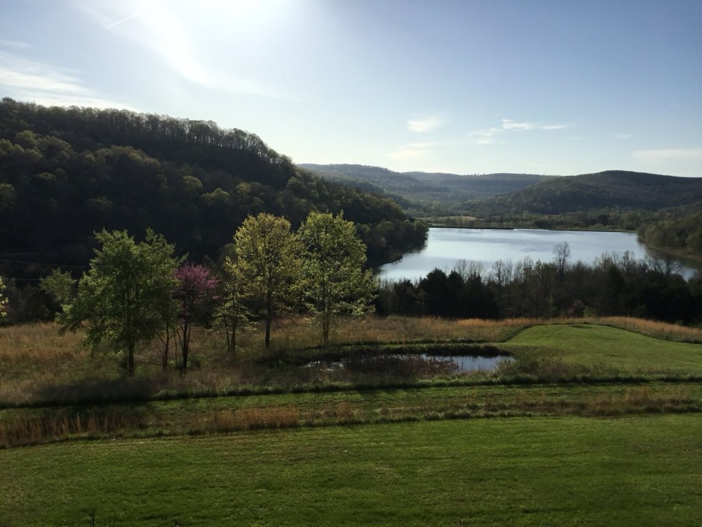 View of the lake below green fields and wooded Ozark hills