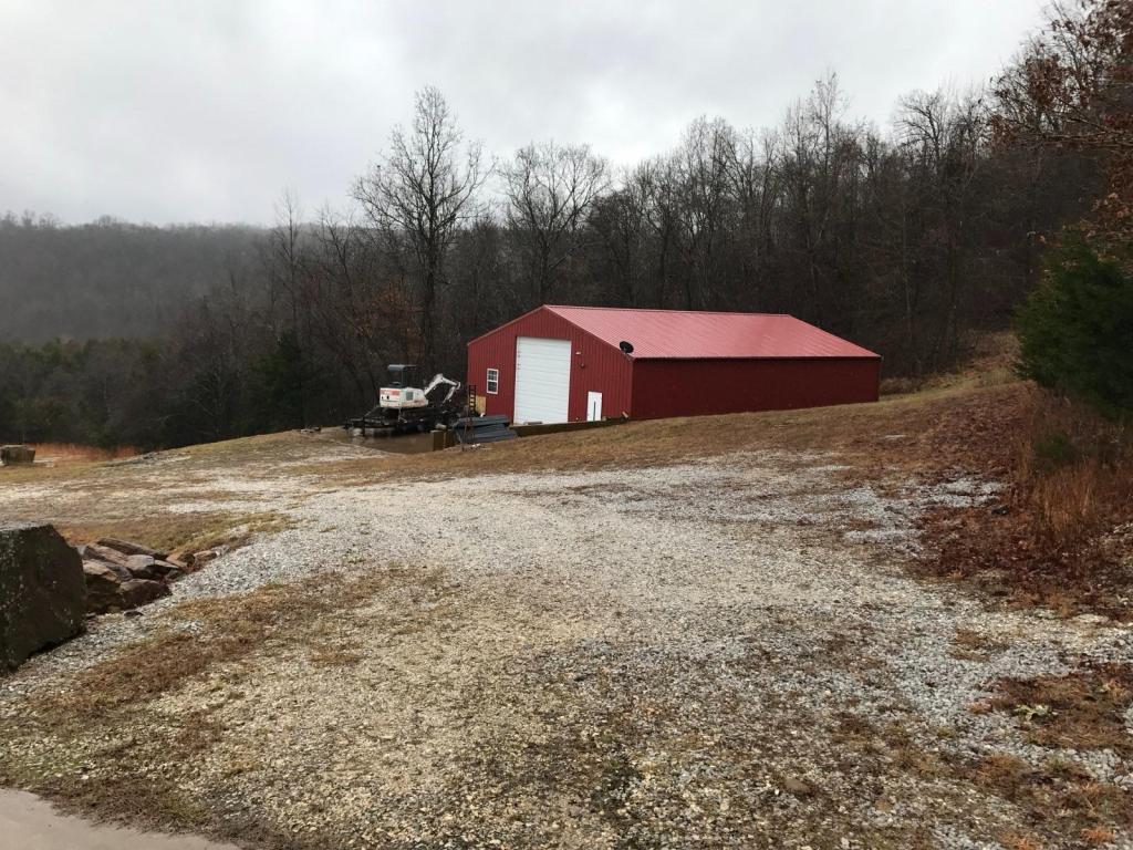 The red metal building at the Living Springs Log House among bare winter trees