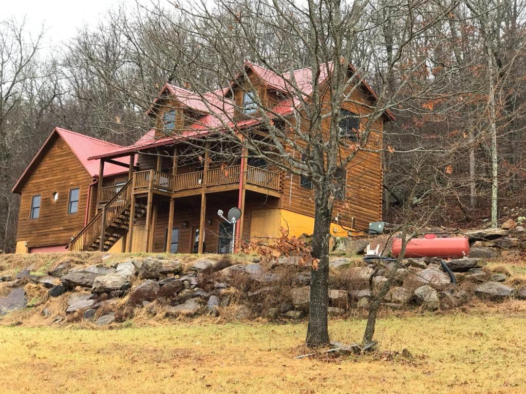 The Living Springs Log House with its red roof among bare winter trees