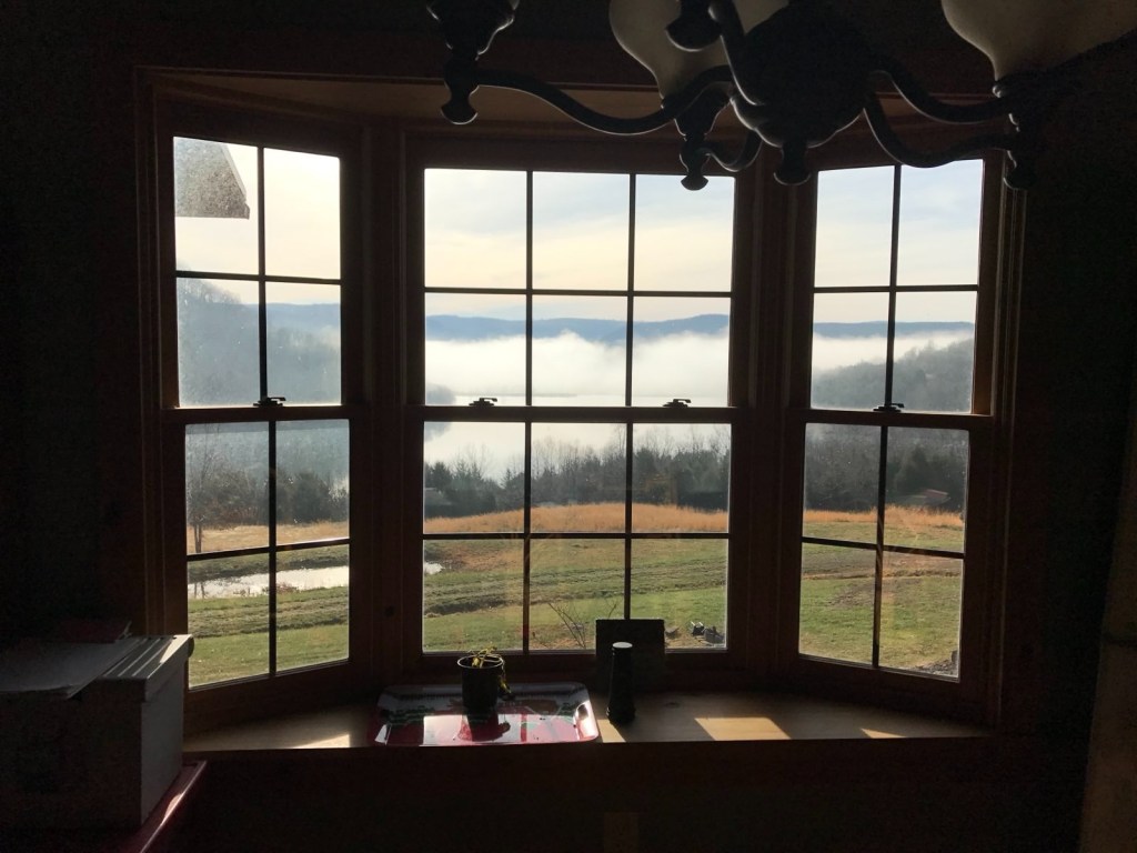 Morning fog over the hills seen through a bay window at the log house